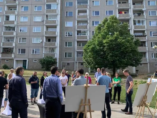 Titulní foto případové studie se záběrem na setkání obyvatel sídliště v ulici, kde se prezentují informace o projektu.
